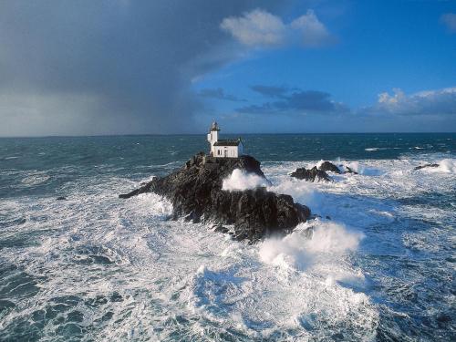 a lighthouse on a rock in the ocean at Holiday Home near Pointe du Raz & Sea in Kersaudy