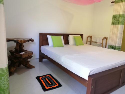 a bedroom with a bed with green and white pillows at Fairview Dill homestay in Sigiriya