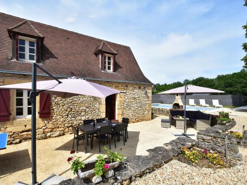 um pátio com uma mesa, cadeiras e guarda-sóis em Cozy Holiday Home in Saint L on sur em Sergeac