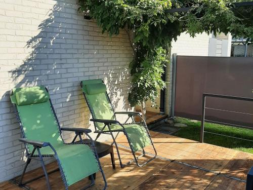 two green chairs sitting next to a wall at Cottage in Durbuy with Terrace Garden Barbecue in Durbuy