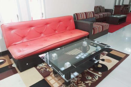 a red leather couch in a living room with a table at RedDoorz Syariah near Komplek Candi Arjuna Dieng 2 in Dieng