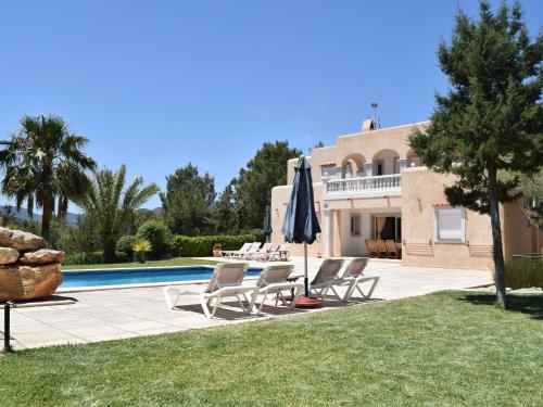 Villa con piscina y patio con sillas y sombrilla. en Belvilla by OYO Can Cova, en Sant Josep