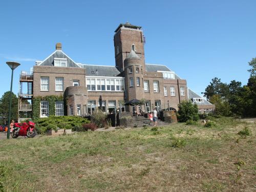 un gran edificio de ladrillo en la cima de una colina en Unique studio on large estate with sea view, en Bergen aan Zee