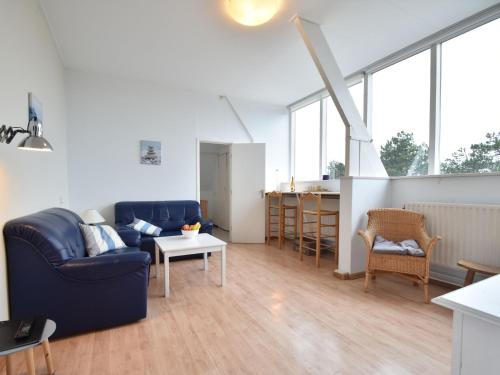 een woonkamer met een blauwe bank en een tafel bij Apartment with stunning views in Bergen aan Zee