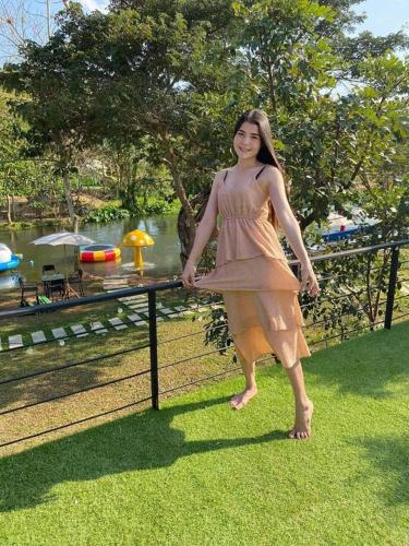 a woman in a dress standing next to a fence at JK Riverview Resort in Ban Song Phi Nong