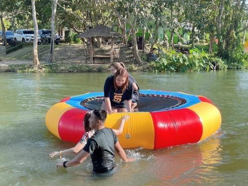 three people in the water on anlatable raft in the water at JK Riverview Resort in Ban Song Phi Nong