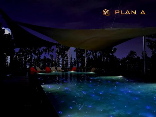 a swimming pool with chairs in the water at night at Opus LIV Signature in Kuala Lumpur