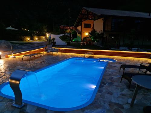 a swimming pool lit up at night at Pousada Rural Altos de Lumiar in Nova Friburgo
