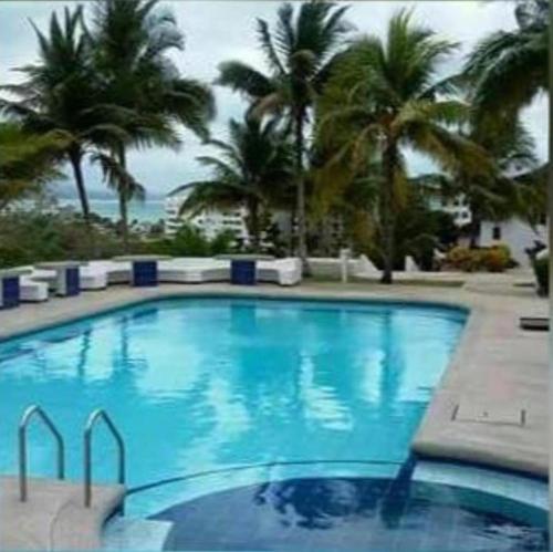 a large blue swimming pool with palm trees and the ocean at DEPAR DE PLAYA Casa Blanca Same in Same