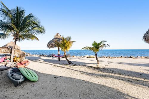 a beach with palm trees and a surfboard on the sand at Kawama Yacht Club A4 in Key Largo