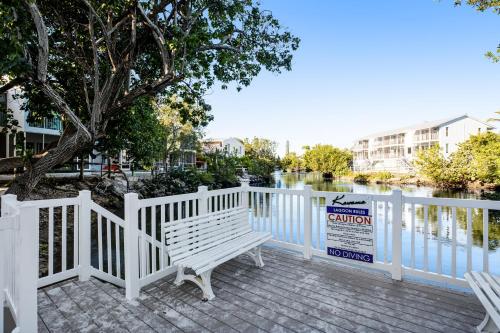 a white fence with a bench next to a river at Kawama Yacht Club A4 in Key Largo