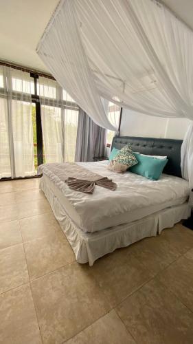 a bed with a canopy in a room with windows at Palmazul Hotel & Spa in San Clemente