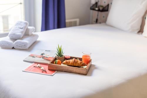 - un plateau de nourriture et de fruits sur un lit dans l'établissement WS Opéra - Galeries Lafayette, à Paris