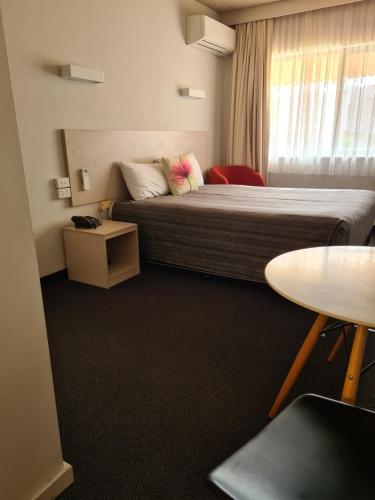 a hotel room with a bed and a table at Belconnen Way Hotel & Serviced Apartments in Canberra