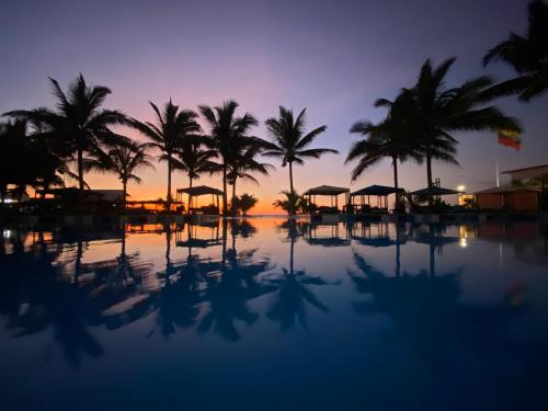 a resort pool with palm trees and a sunset at Palmazul Hotel & Spa in San Clemente