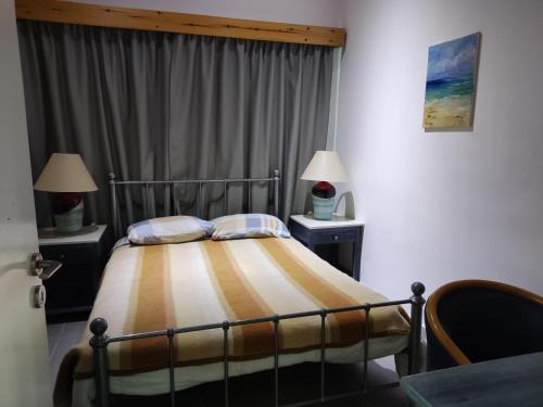 a bedroom with a bed with two night stands and two lamps at Wooden House in Paphos City