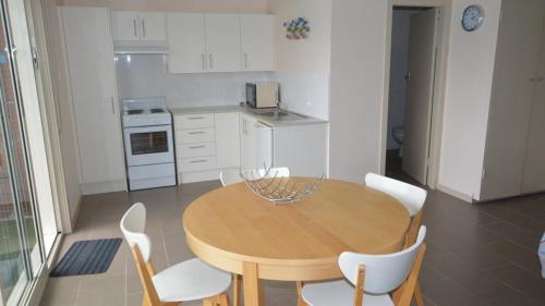 a kitchen with a wooden table and white chairs at HIBBARD HAVEN in Port Macquarie