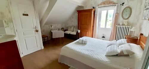 ein Schlafzimmer mit einem weißen Bett und einem Fenster in der Unterkunft Les Champs de Tracy in La Graverie