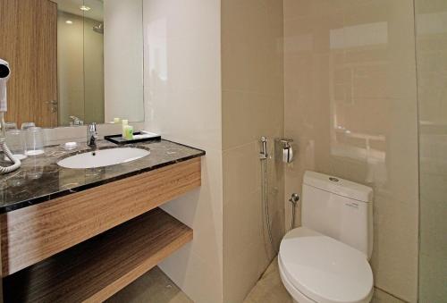a bathroom with a toilet and a sink and a mirror at Swiss-Belhotel Manokwari in Manokwari