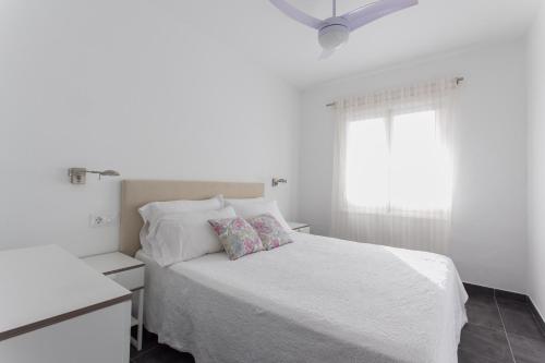 Un dormitorio blanco con una cama blanca y una ventana en Apartamento estudio GAMA, en Cala Galdana