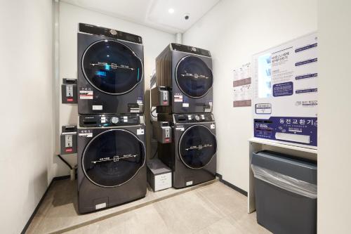 three washing machines are stacked against a wall at Nine Tree by Parnas Seoul Dongdaemun in Seoul