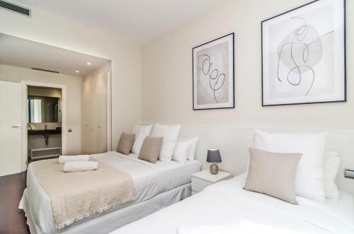 two beds in a room with white walls at Sitges Spaces Garden Paradise 3 bedroom, 3 bathroom, huge PRIVATE garden-terrace, pool- sleeps up to 8 in Sitges