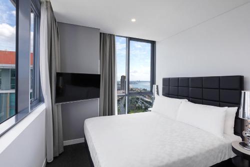 a bedroom with a white bed and a large window at Meriton Suites Southport in Gold Coast