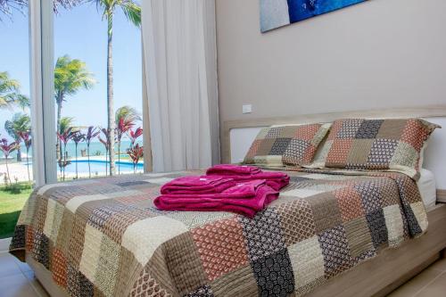 uma cama com um cobertor com palmeiras em CARNEIROS EXPERIENCE! Conforto e Pé na areia! em Tamandaré