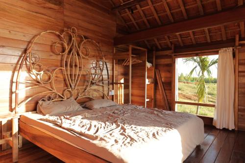 ein Schlafzimmer mit einem großen Bett in einem Holzzimmer in der Unterkunft TODO Farm - Organic Farming & Retreat in Phu Yen