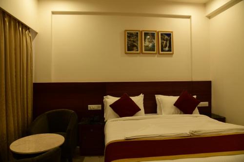 a hotel room with a bed with a table and a chair at Hotel U.T.ELITE in Bengaluru