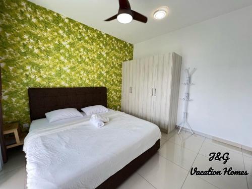 a bedroom with a white bed with a green wall at The Garden By J&G Vacation Homes in Skudai