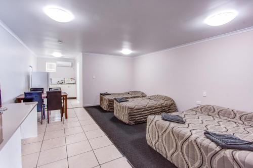 a room with two beds and a kitchen with a table at Galaxy Mackay Motor Inn in Mackay