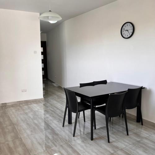 a black dining room table with chairs and a clock on a wall at F6 Room 2, Private Room two single beds shared bathroom in shared Flat in Msida