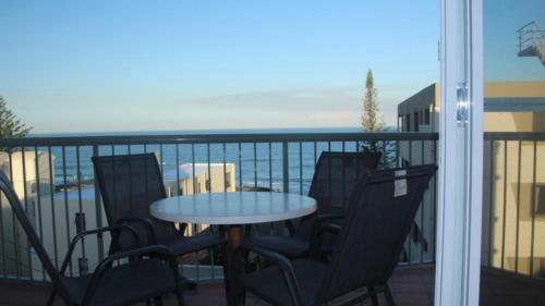 uma mesa e cadeiras numa varanda com vista para o oceano em Unit 5 Sanctuary Shores, Kings Beach - Free Wifi! em Caloundra