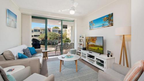 a living room with a couch and a tv at Unit 2 'fair Haven' Kings Beach in Caloundra