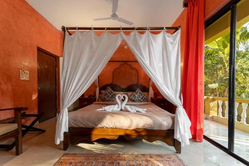 a bedroom with a bed with a canopy at juSTa Morjim Beach Resort Goa - 80 Steps from Morjim Beach in Morjim