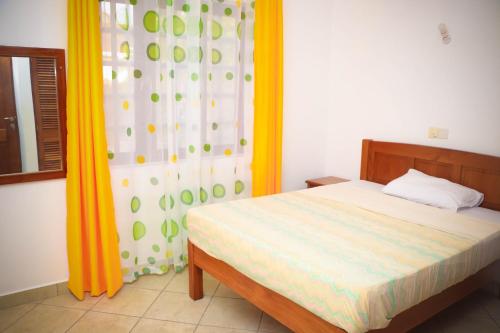 a bedroom with a bed and a curtain and a window at V-Szameitat Homes in Diani Beach