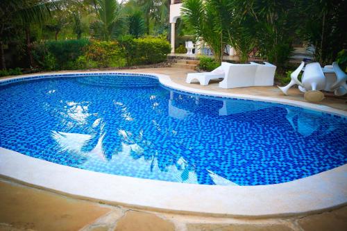 a large swimming pool with blue water in a yard at V-Szameitat Homes in Diani Beach