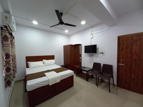 1 dormitorio con 1 cama, escritorio y TV en VEERAS HOME STAY, en Port Blair