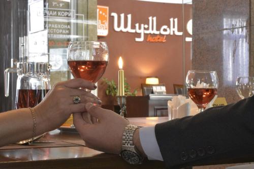 two people are holding glasses of wine at a bar at Hotel Shumon in Dushanbe
