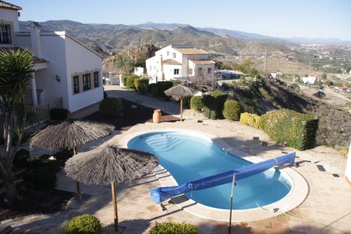 a swimming pool with umbrellas and a house at Villa Rosada - luxurious 3-bedroom villa with garden and pool in Cantoria