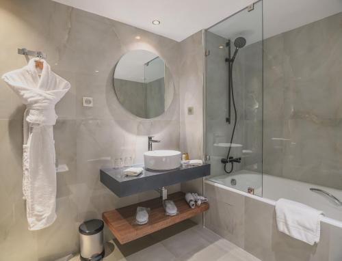 a bathroom with a sink and a tub and a mirror at Idou Anfa Hôtel & Spa in Casablanca
