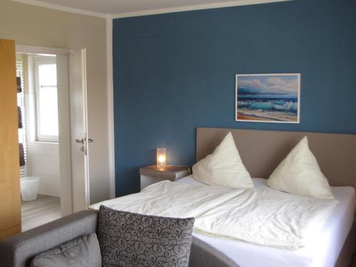 a bedroom with a bed with a blue wall at Strandhotel-Najade in Borkum