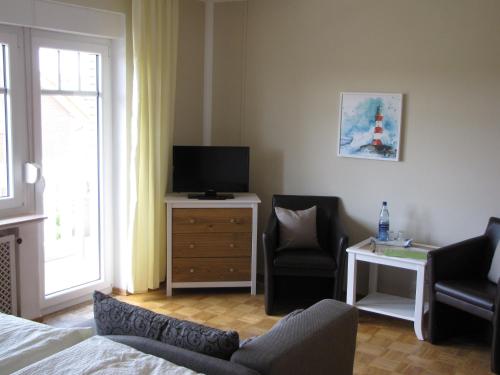 a bedroom with a bed and a tv and a chair at Strandhotel-Najade in Borkum