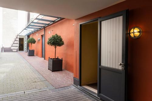 a hallway with orange walls and a door with a plant at Dukes' Arches Brugge - by Dukes' Hotel Collection in Bruges