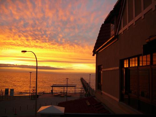 a sunset over the ocean with a picnic table at McCloud House in Port Noarlunga
