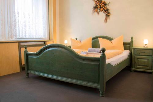 un letto verde con cuscini arancioni in una camera da letto di Bürgerhaus Niesky a Niesky