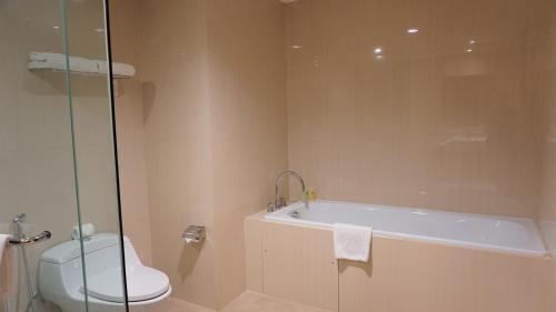 a bathroom with a tub and a toilet and a sink at Swiss-Belhotel Makassar in Makassar