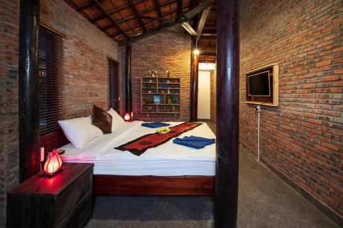 a bedroom with a bed in a brick wall at An Vien Coffee & Villa in Hoi An