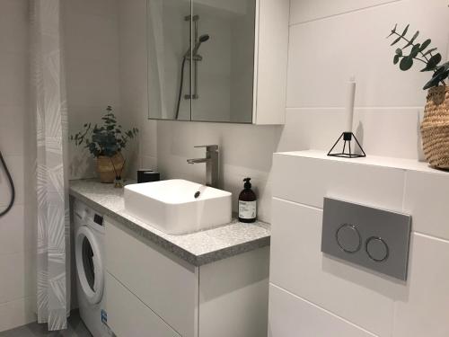 a white bathroom with a sink and a washing machine at Mysig studiolägenhet i Västra Göteborg in Västra Frölunda